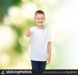 advertising, ecology, gesture, people and childhood concept - smiling boy in white blank t-shirt showing thumbs up over green background