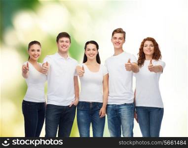 advertising, ecology, nature, friendship and people concept - group of smiling teenagers in white blank t-shirts showing thumbs up over green background