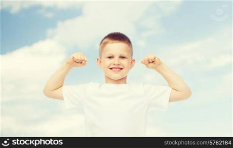 advertising, ecology, people and childhood concept - smiling little boy in white blank t-shirt flexing biceps over blue sky background