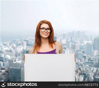 advertising, education and people concept - smiling teenage girl in glasses with blank white board over city background