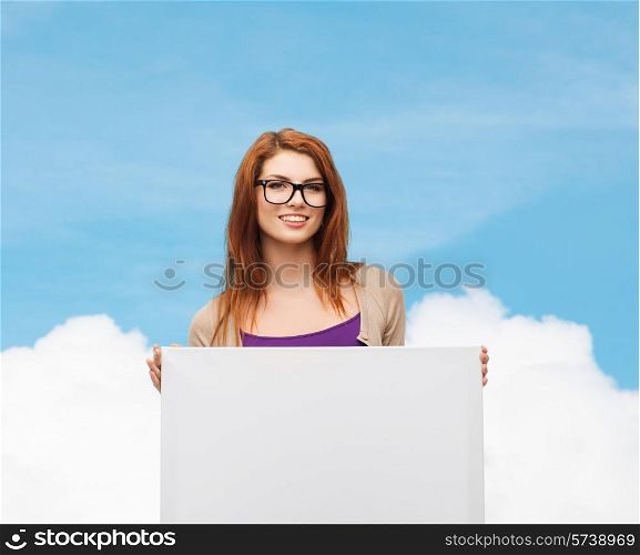 advertising, education and people concept - smiling teenage girl in glasses with blank white board over blue sky and cloud background