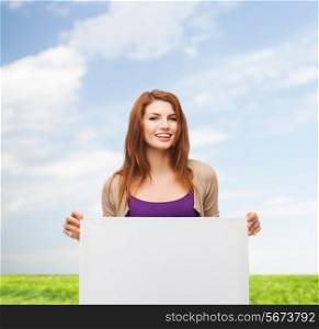 advertising, education and people concept - smiling teenage girl with blank white board over blue sky and grass background