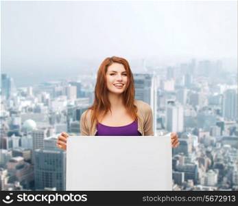 advertising, education and people concept - smiling teenage girl with blank white board over city background