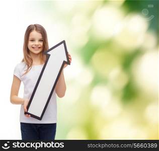 advertising, environment, direction and childhood concept - smiling little girl with white blank arrow pointing up over natural background