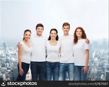 advertising, friendship, and people concept - group of smiling teenagers in white blank t-shirts over city background