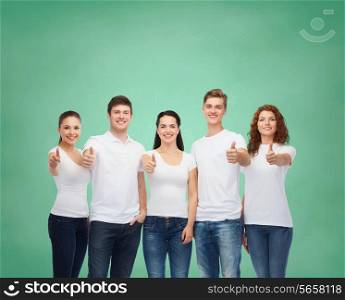 advertising, friendship, education, school and people concept - group of smiling teenagers in white blank t-shirts showing thumbs up over green board background