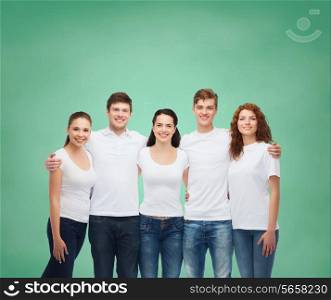 advertising, friendship, education, school and people concept - group of smiling teenagers in white blank t-shirts standing over green board background