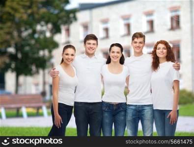 advertising, friendship, education, scool and people concept - group of smiling teenagers in white blank t-shirts over campus background