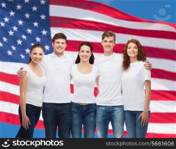 advertising, friendship, patriotism and people concept - group of smiling teenagers in white blank t-shirts over american flag background