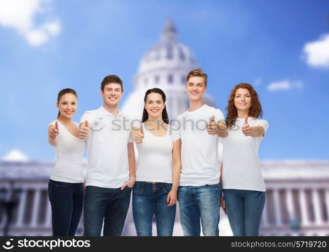advertising, friendship, tourism and people concept - group of smiling teenagers in white blank t-shirts showing thumbs up over over white house background