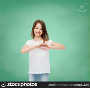 advertising, gesture, charity, education and people - smiling little girl in white blank t-shirt over green board background