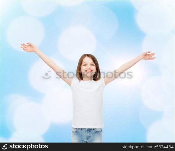 advertising, gesture, childhood and people - smiling little girl in white blank t-shirt with stretched out arms over blue background