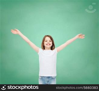 advertising, gesture, education, childhood and people - smiling girl in white t-shirt with stretched out arms over green board background