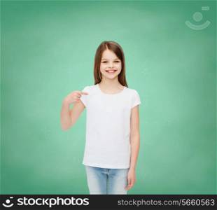 advertising, gesture, education, childhood and people - smiling girl in white t-shirt pointing finger on herself over green board background