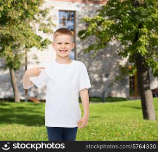 advertising, gesture, people and childhood concept - smiling boy in white blank t-shirt pointing finger at himself over campus background