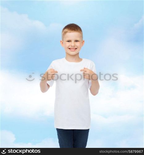 advertising, gesture, people and childhood concept - smiling boy in white t-shirt pointing fingers at himself over cloudy sky background