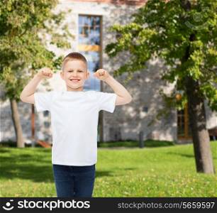 advertising, gesture, people and childhood concept - smiling little boy in white blank t-shirt with raised hands over campus background