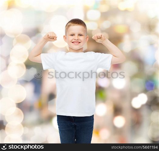 advertising, gesture, people and childhood concept - smiling little boy in white blank t-shirt ith raised hands over holidays background