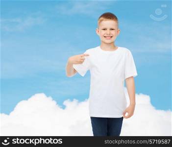 advertising, gesture, people and childhood concept - smiling little boy in white t-shirt pointing finger at himself over sky background