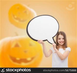 advertising, information, holidays, childhood and people concept - smiling little girl holding white text bubble over halloween pumpkins background