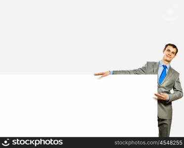 Advertising manager. Image of young man holding blank banner with crowd of business people at background