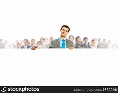 Advertising manager. Image of young man holding blank banner with crowd of business people at background