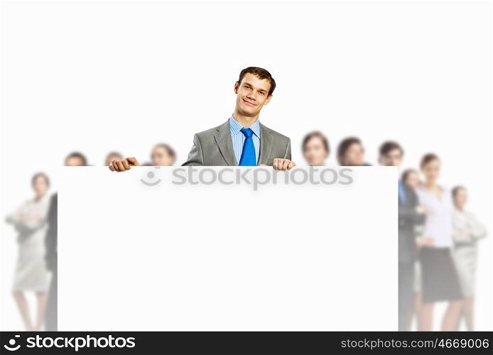 Advertising manager. Image of young man holding blank banner with crowd of business people at background
