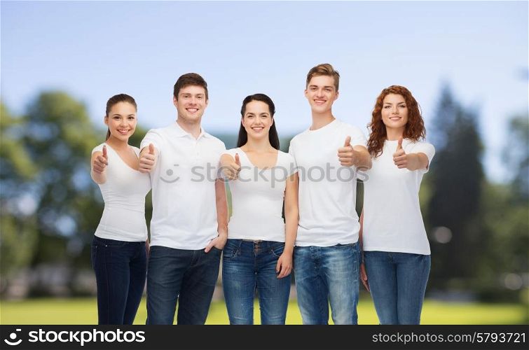 advertising, nature, summer holidays and people concept - group of smiling teenagers in white blank t-shirts showing thumbs up