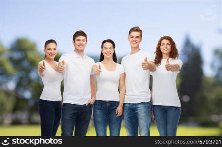 advertising, nature, summer holidays and people concept - group of smiling teenagers in white blank t-shirts showing thumbs up