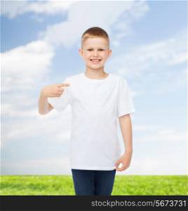 advertising, people and childhood concept - smiling little boy in white blank t-shirt pointing finger at himself over natural background