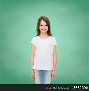 advertising, school, education, childhood and people - smiling little girl in white blank t-shirt over green board background