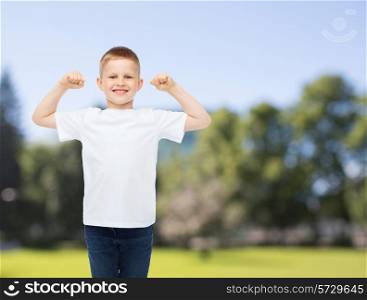 advertising, summer, people and childhood concept - smiling little boy in white blank t-shirt with raised hands over park background