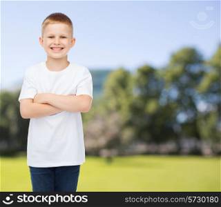 advertising, summer, people and childhood concept - smiling little boy in white blank t-shirt over park background