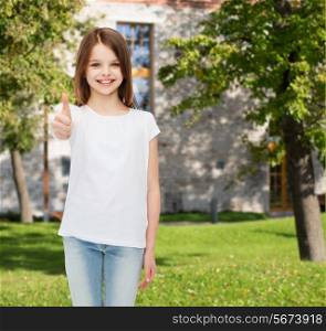 advertising, summer vacation, gesture, childhood and people - smiling little girl in white t-shirt showing thumbs up over campus background