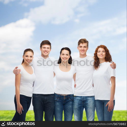 advertising, summer vacation, nature, friendship and people - group of smiling teenagers in white blank t-shirts over blue sky and grass background