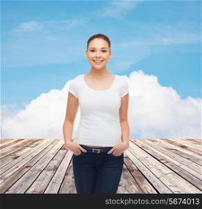 advertising, vacation and people concept - smiling young woman in blank white t-shirt over wooden berth and blue sky background