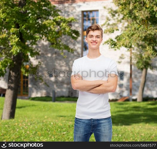 advertising, vacation, education and people concept - smiling young man in blank white t-shirt over campus background