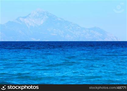 Aegean sea coast landscape with aquamarine water and Mount Athos in mist (view from Chalkidiki, Greece).