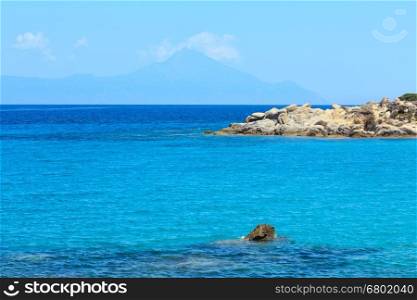 Aegean sea coast landscape with aquamarine water and Mount Athos in mist, view near Karidi beach (Chalkidiki, Greece).