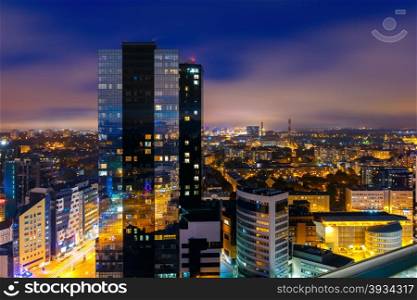 Aerial cityscape of modern business financial district with tall skyscraper buildings illuminated at night, Tallinn, Estonia