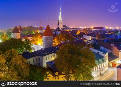 Aerial cityscape with Medieval Old Town, St. Olaf Baptist Church and Tallinn City Wall illuminated at autumn night, Tallinn, Estonia