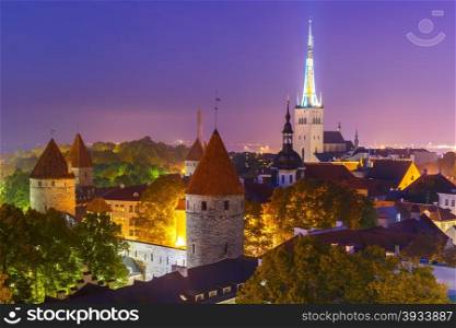 Aerial cityscape with Medieval Old Town, St. Olaf Baptist Church and Tallinn City Wall illuminated at autumn night, Tallinn, Estonia