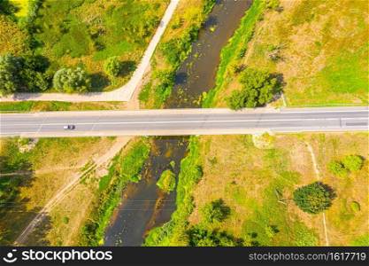 aerial drone shoot. Flying over a beautiful green forest in a rural landscape. Top view of trees in forest background. Drone photography. Forest river, rural road.