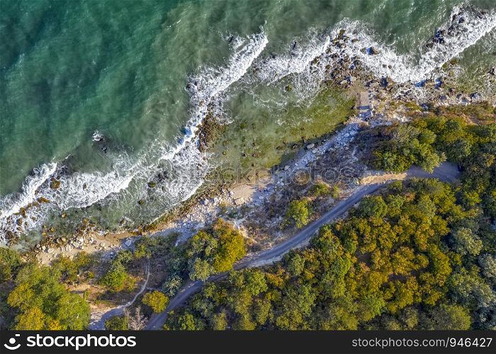 Aerial drone view of coastline surface with waves and rocks. Top view