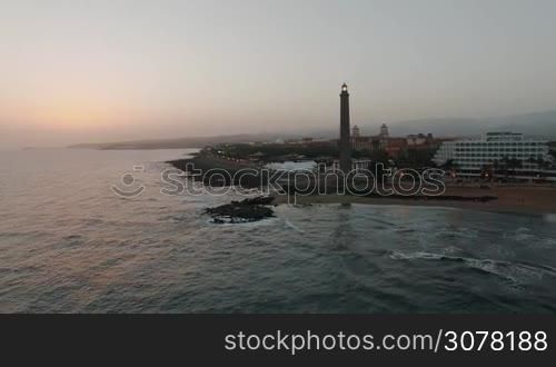 Aerial evening scene of resort on the coast with lighthouse. Maspalomas, Gran Canaria