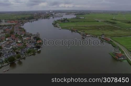 Aerial flight above the Koog Zaandijk, Netherlands. View of town on the one side of river and agricultural fields on the other side