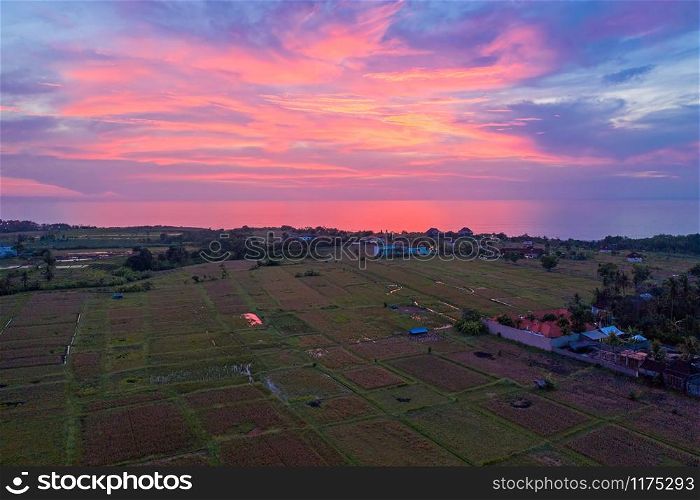 Aerial from an incredible sunset from rice fields and indian ocean at the west coast from Bali in Indonesia
