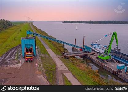 Aerial from freighter unloading sand in the countryside from the Netherlands at sunset