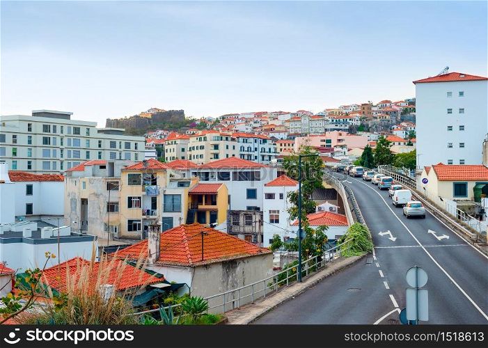Aerial Funchal cityscape, traffic on hill road, residential houses with red rooftops, Madeira, Portugal
