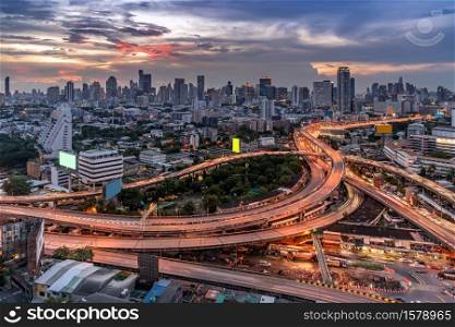 Aerial High angel view of Bangkok downtown highway toll expressway with skyscraper building skylines at sunset dusk. Transportation infrastructure concept.